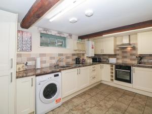 una cucina con mobili bianchi, lavatrice e asciugatrice di Old Hall Cottages ad Ashbourne