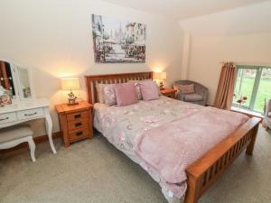 una camera da letto con un letto, una scrivania e uno specchio di Old Hall Cottages ad Ashbourne