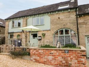 un cane seduto di fronte a una casa di mattoni di Old Hall Cottages ad Ashbourne