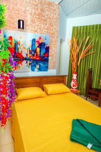 a yellow bed in a bedroom with a painting on the wall at hotel lake freedom in Panadura
