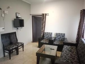 ナイニタールにあるNainigreen Valley Kainchidham Luxurious Homestayの椅子2脚とテレビのあるリビングルーム