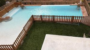 a large swimming pool with a wooden fence and water at La villa de Naomi in Chella