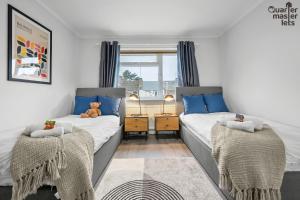 2 Betten in einem Schlafzimmer mit einem Teddybär auf dem Bett in der Unterkunft 5 Bedroom Central Townhouse with Parking that Sleeps 9 in Leamington Spa
