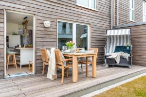 a wooden deck with a table and chairs on it at Ferienwohnung HafenloungeOlpenitz in Olpenitz