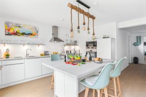a kitchen with white cabinets and a large island with blue chairs at Ferienwohnung HafenloungeOlpenitz in Olpenitz
