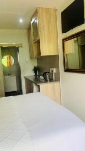 a bedroom with a white bed and a kitchen at Pinetown Accommodation in Pinetown