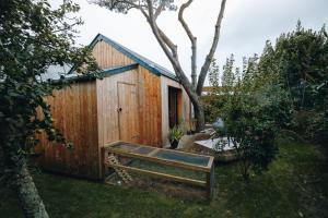 a wooden shed with a bench next to a tree at Le Poulailler Spa & Sauna in Auderville