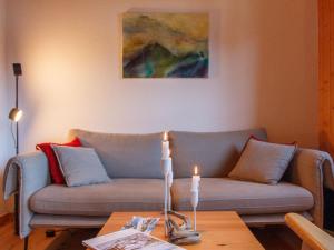 a living room with a couch and a table with a candle at Apartment Dahlia by Interhome in Champoussin