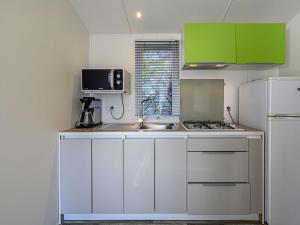 カルナックにあるApartment Le Courlis by Interhomeの白いキャビネット、シンク、冷蔵庫付きのキッチンが備わります。
