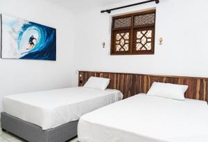 two beds in a room with a painting on the wall at Avocado Retreat in Kandy