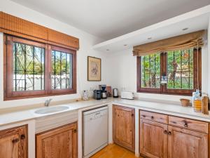 a kitchen with wooden cabinets and a sink and windows at Villa La Familia by Interhome in Benissa