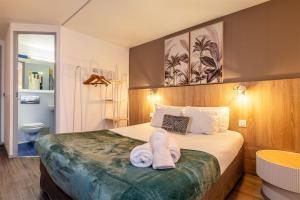 a hotel room with a bed with towels on it at Hôtel Le Roxane in Bergerac