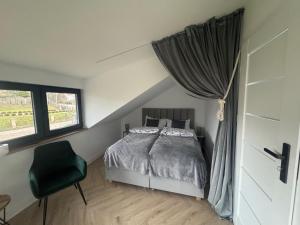 a bedroom with a bed and a chair and a window at Borowe Apartamenty in Borowe