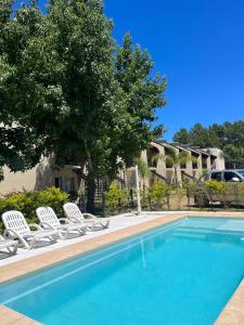 a swimming pool with two lawn chairs and a tree at Brisas del Lago Apartamentos in Colón