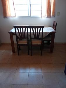 a wooden table and two chairs and a table and a window at Casita en las sierras in Huerta Grande
