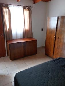 a bedroom with a bed and a dresser and a window at Casita en las sierras in Huerta Grande
