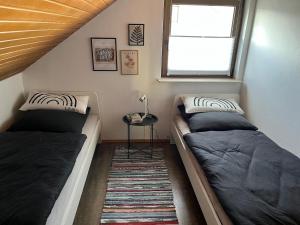 two beds in a room with a window and a table at Ferienwohnung mit Kreuzbergblick in Bischofsheim an der Rhön