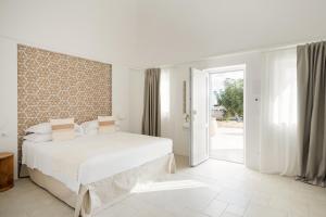 a white bedroom with a large bed and sliding glass doors at Borgo Tufaia in Fasano +66 photos