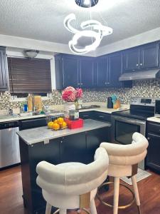 a kitchen with blue cabinets and a counter with two stools at Comfortable King Bedroom within A HOME WITH HOSTS in Columbus