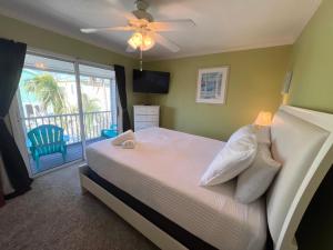 a bedroom with a bed with a ceiling fan and a balcony at Tropical Terrace 3 in Holmes Beach