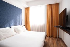 sypialnia z białym łóżkiem i dużym oknem w obiekcie Hotel IMPERATORI w Rzymie