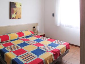 ein Schlafzimmer mit einem Bett mit einer bunten Steppdecke in der Unterkunft Holiday Home La Quercia-2 by Interhome in La Fagiana