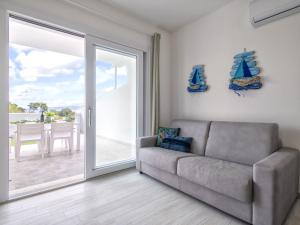a living room with a couch and a sliding glass door at Apartment La terrazza sulla piscina by Interhome in Valledoria