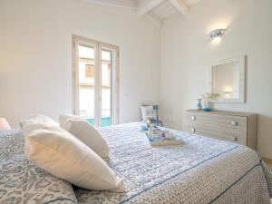 a white bedroom with a bed with pillows and a dresser at Holiday Home La Conchiglia D'oro by Interhome in Budoni
