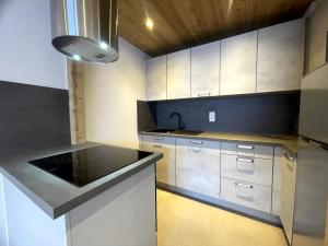 a kitchen with white cabinets and a black counter top at GROTTE AUX FEES A, appartement skis aux pieds in La Clusaz