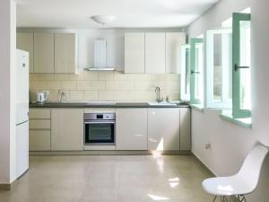 eine Küche mit weißen Schränken und einem weißen Stuhl darin in der Unterkunft Holiday Home Villa Portobello Green by Interhome in Labin