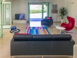 ein Wohnzimmer mit einem schwarzen Sofa und roten Stühlen in der Unterkunft Holiday Home Villa Portobello Green by Interhome in Labin