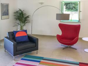 ein Wohnzimmer mit einem Stuhl und einem roten Stuhl in der Unterkunft Holiday Home Villa Portobello Green by Interhome in Labin