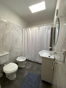 a white bathroom with a toilet and a sink at Cabañas Vicentico in Mina Clavero +9 photos