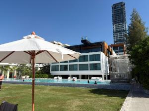 a white umbrella sitting in the grass next to a building at 芭提雅日瓦达酒店式公寓 in Na Jomtien