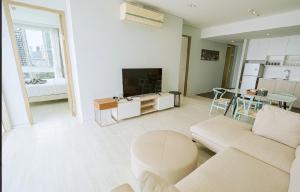 a living room with a couch and a tv at 芭提雅日瓦达酒店式公寓 in Na Jomtien