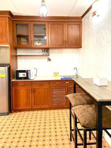 a kitchen with wooden cabinets and a table with chairs at Impact Arena Condo The Classic by GoodRoom24 in Ban Song Hong +4 photos