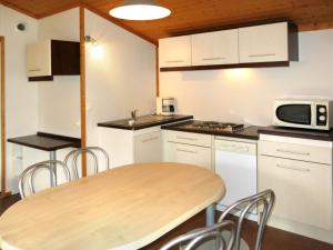 a kitchen with a wooden table and a microwave at Holiday Home Les Hameaux de Miel-Chalet 4 pers- by Interhome in Beynat