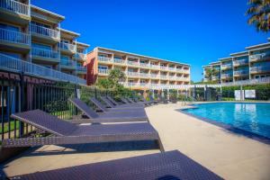 una fila de bancos junto a un edificio con piscina en Billy's Bungalow 1bd Heated pools Steps to the beach, en Galveston