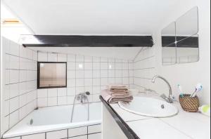 巴黎Votre suite entre Belleville et Canal的带浴缸和水槽的白色浴室 更多4张照片