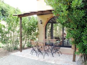 un patio con mesa y sillas bajo una pérgola en Apartment Istrice-30 by Interhome, en Riparbella