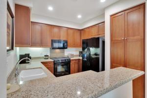 a kitchen with wooden cabinets and a black refrigerator at Secluded Ground Floor 1BR Villa #A in La Quinta