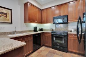 a kitchen with wooden cabinets and black appliances at Secluded Ground Floor 1BR Villa #A in La Quinta