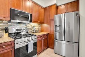a kitchen with wooden cabinets and a stainless steel refrigerator at Modern LQ Getaway Steps to pool & spa #A in La Quinta