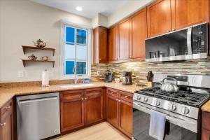 a kitchen with wooden cabinets and stainless steel appliances at Modern LQ Getaway Steps to pool & spa #A in La Quinta