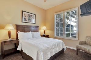 a bedroom with a bed and a chair and a window at Desert Oasis Villa #A Steps from Pool in La Quinta