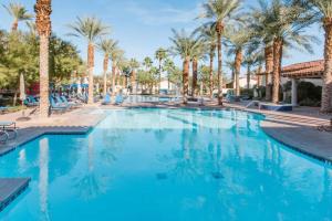 a swimming pool at a resort with palm trees at Desert Oasis Villa #A Steps from Pool in La Quinta