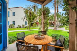 a wooden table and chairs on a patio with a yard at Revitalized Desert Getaway #A in La Quinta