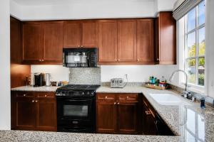 a kitchen with wooden cabinets and a black stove at Remodeled Desert Hideaway #A in La Quinta