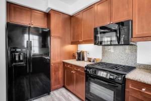 a kitchen with wooden cabinets and black appliances at Remodeled Desert Hideaway #A in La Quinta +21 photos