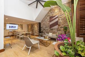 eine Lobby mit Stühlen und Tischen und einer Steinmauer in der Unterkunft Villas La Fontana Amplias ApartaSuite-Piscina 203 in Panama-Stadt